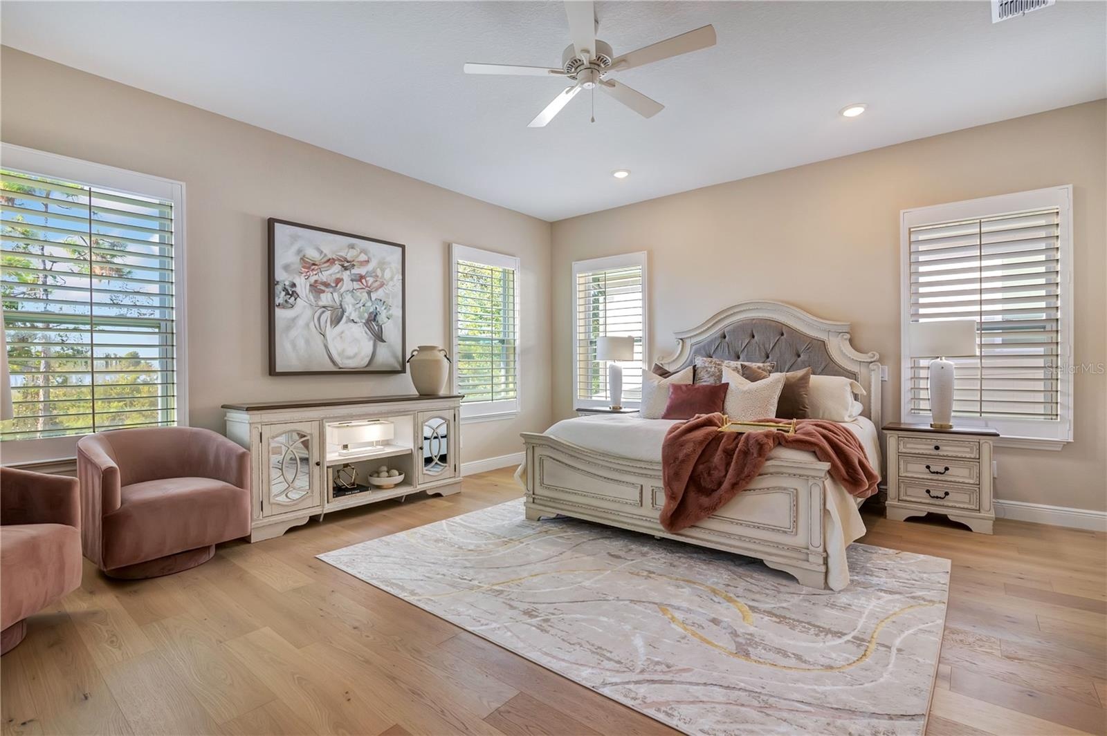 Spacious master featuring hardwood flooring, plantation shutters and abundant natural light, with room for a sitting area.