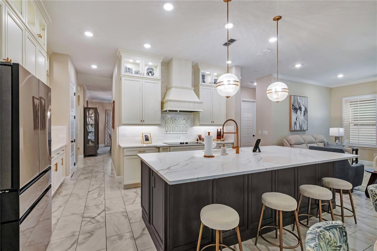 Upgraded kitchen featuring an oversized island with seating, contrasting cabinetry and designer pendant lighting.