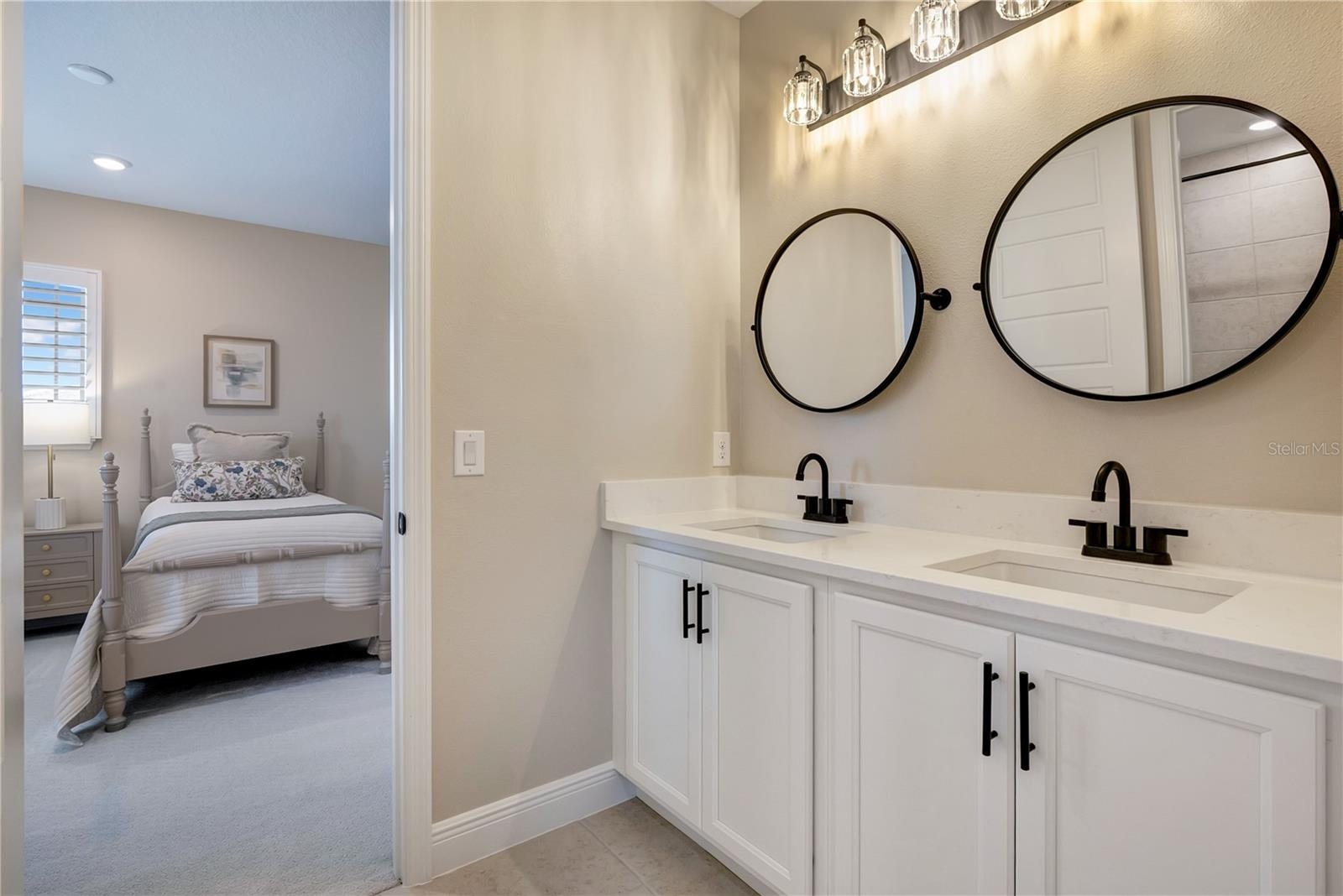 Double-sink vanity featuring white cabinetry, contrasting black fixtures and coordinating round mirrors.