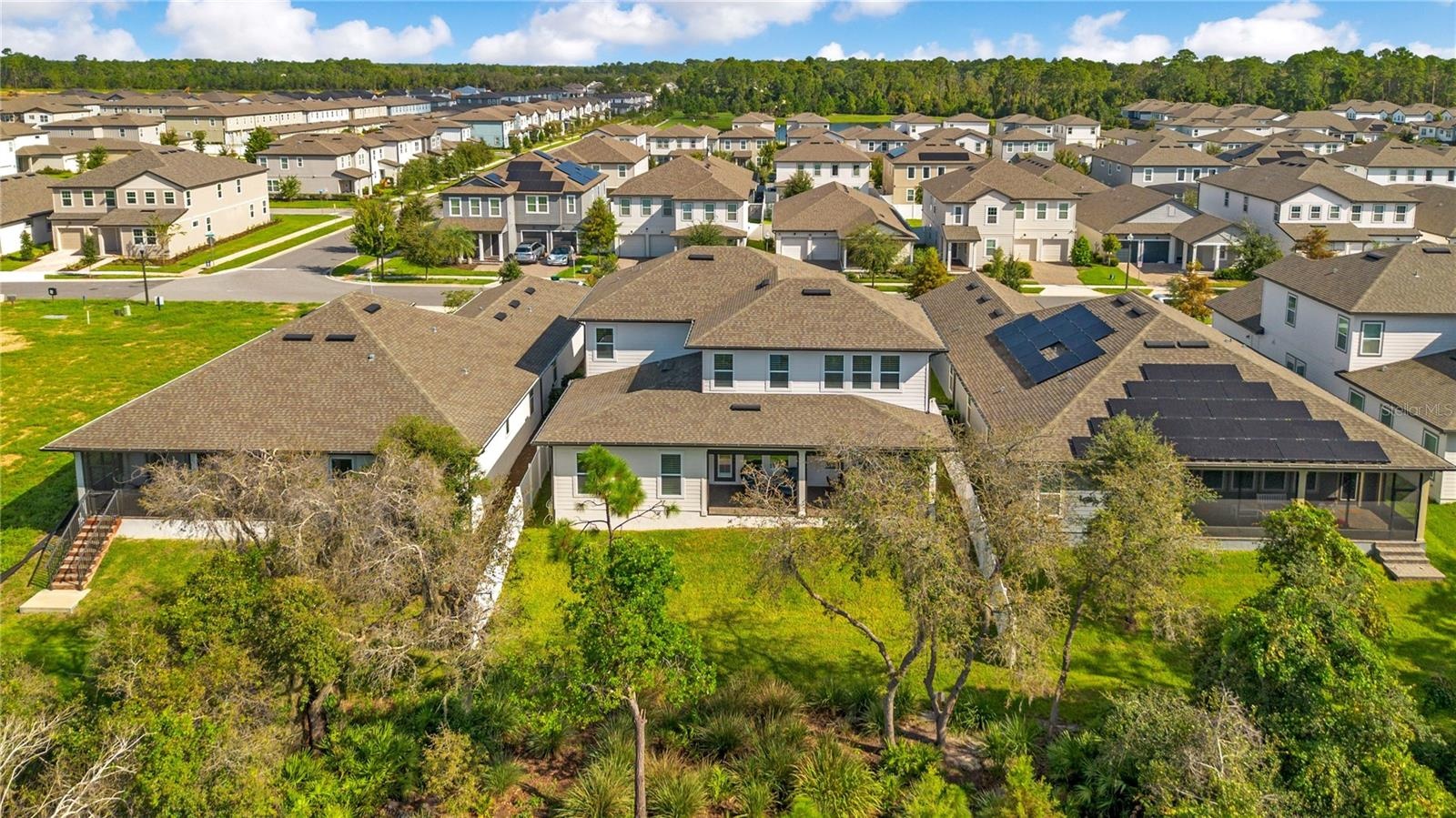 Rear aerial view highlights the spacious backyard, covered lanai and mature trees.