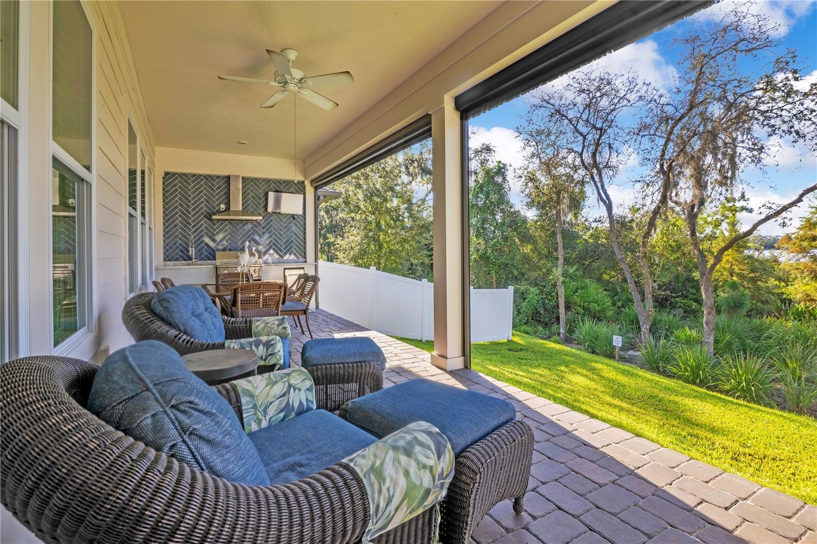 Covered paver lanai offers a relaxing outdoor lounge overlooking the backyard and mature trees.