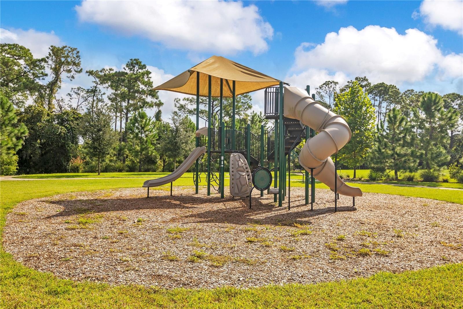 Community playground featuring climbing structures and slides in an open grassy setting.