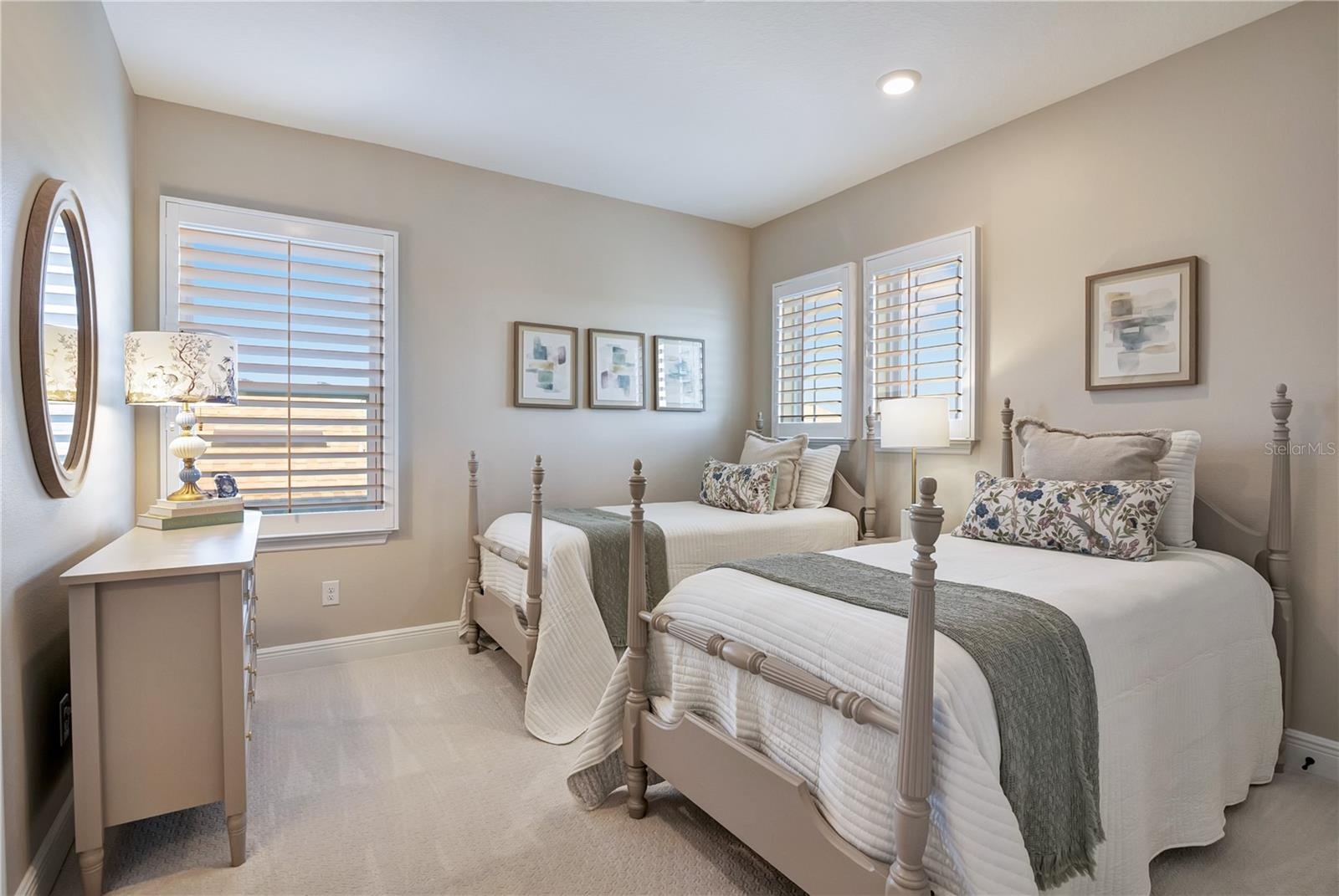 Comfortable bedroom featuring plush carpet, recessed lighting and plantation shutters.