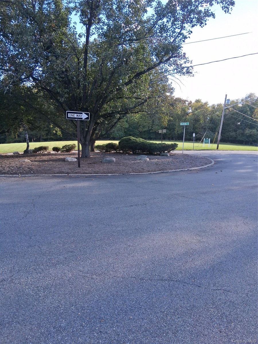 Landscaped island featuring mature deciduous trees, manicured shrubs, and stone border detailing.Frint door view.UNGAVA PARK
