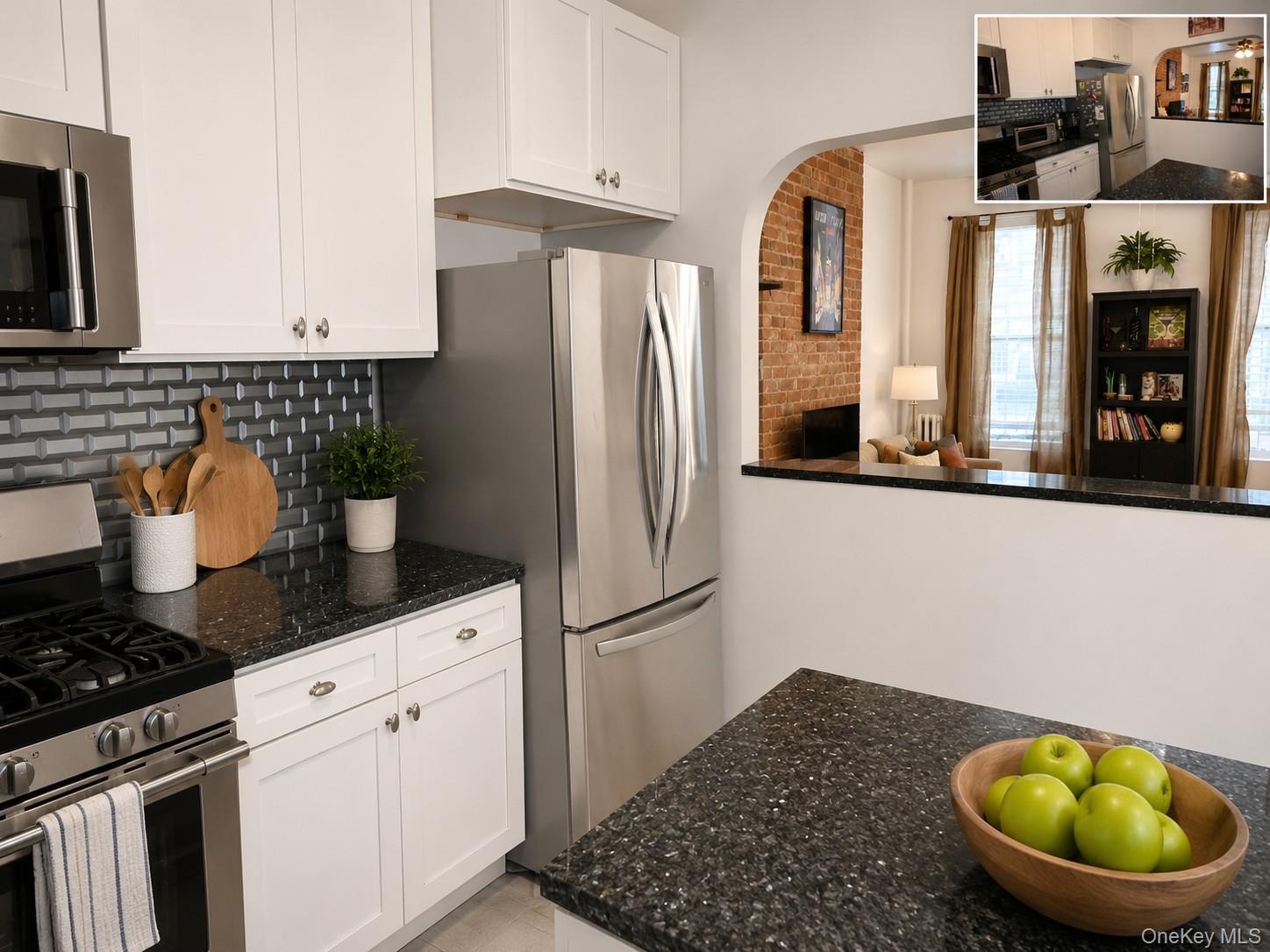 Contemporary kitchen featuring white cabinetry, dark speckled countertops, and a gray subway tile backsplash (virtually staged)