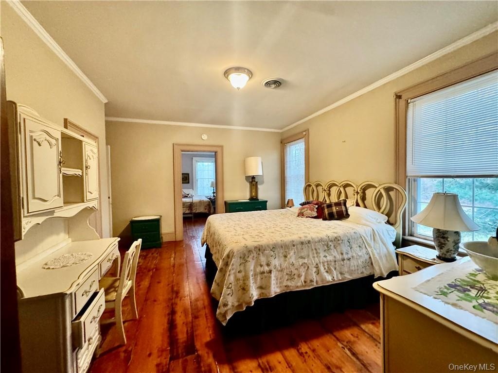 Bedroom with ornamental molding and dark wood-type flooring