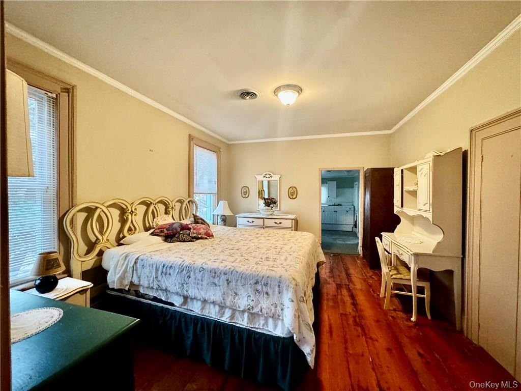 Bedroom with ornamental molding and dark hardwood / wood-style flooring
