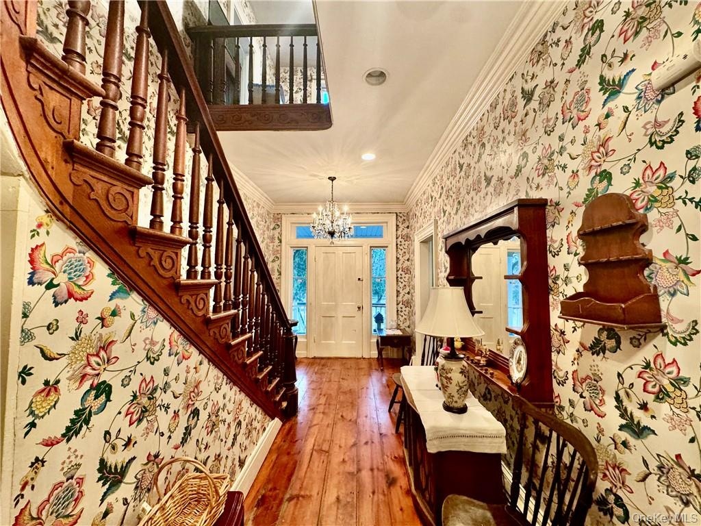 Foyer entrance featuring crown molding, a notable chandelier, and hardwood / wood-style floors