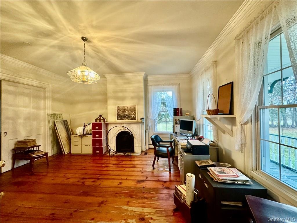 Home office featuring crown molding, a healthy amount of sunlight, wood-type flooring, and a chandelier