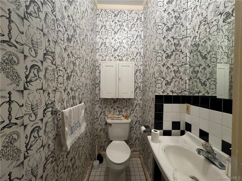 1st floor Bathroom featuring toilet, tile patterned flooring, ornamental molding, sink, and tile walls