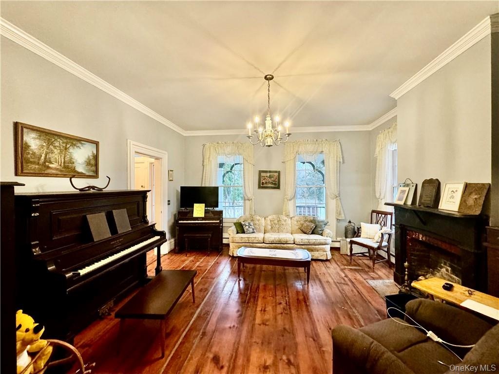 Living room featuring crown molding, a notable chandelier, and wood-type flooring