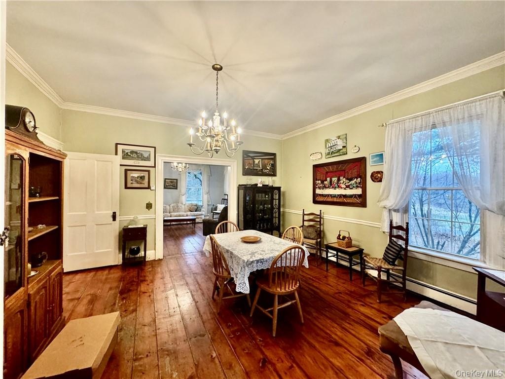 Dining room with ornamental molding, a chandelier, and dark hardwood / wood-style flooring