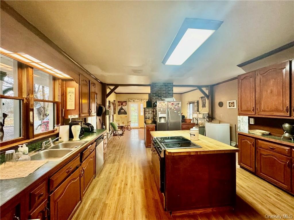 Kitchen featuring stainless steel appliances, sink, a center island, light wood-type flooring, and a skylight
