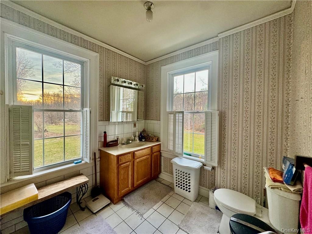 Bathroom with vanity, tile patterned flooring, toilet, and plenty of natural light