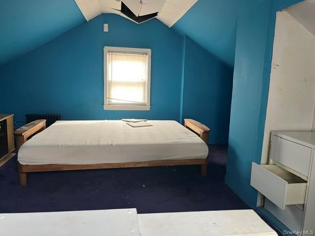 Bedroom with vaulted ceiling and radiator heating unit
