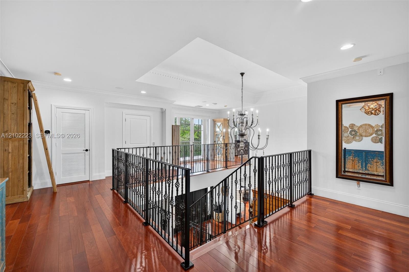 An impressive, second floor Landing overlooks the grand foyer below, showcasing, beautiful hardwood floors, decorative rod, iron railings, and strikin