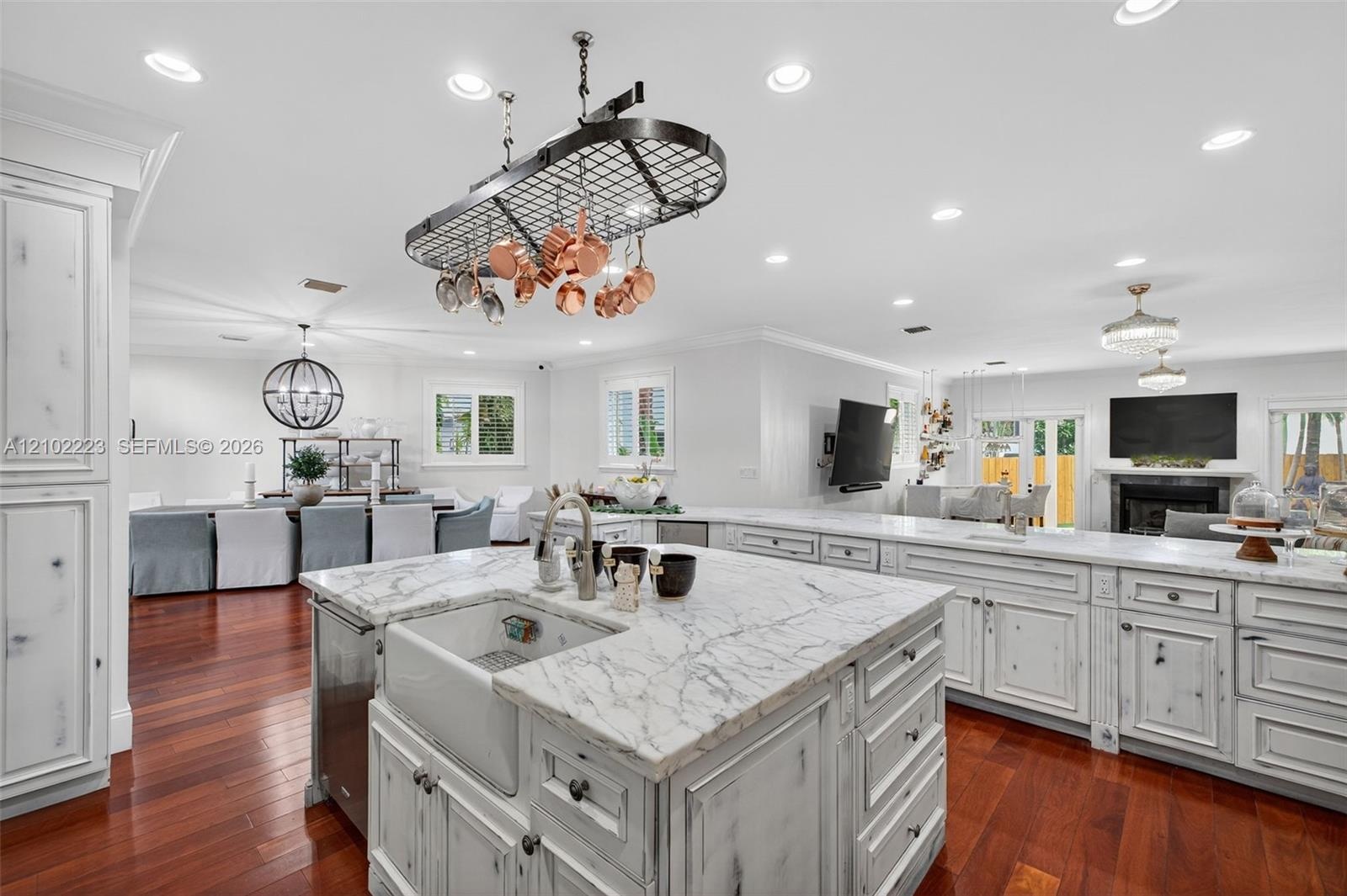 A kitchen design with the culinary enthusiast in mind, beautiful stone countertops, a farmhouse sink and a distinctive, suspended pot rack at characte