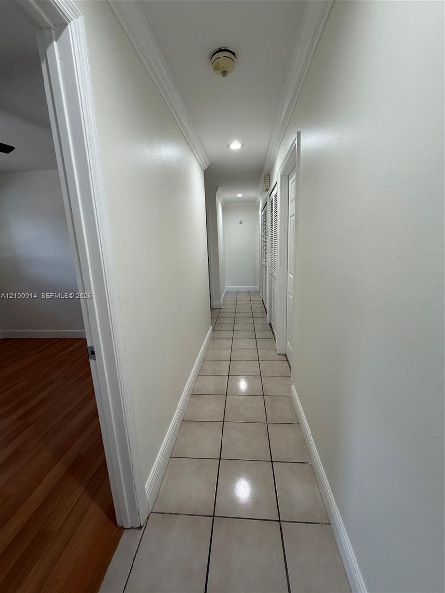 Hallway featuring ceramic tile flooring, recessed lighting, and built-in louvered closet doors
