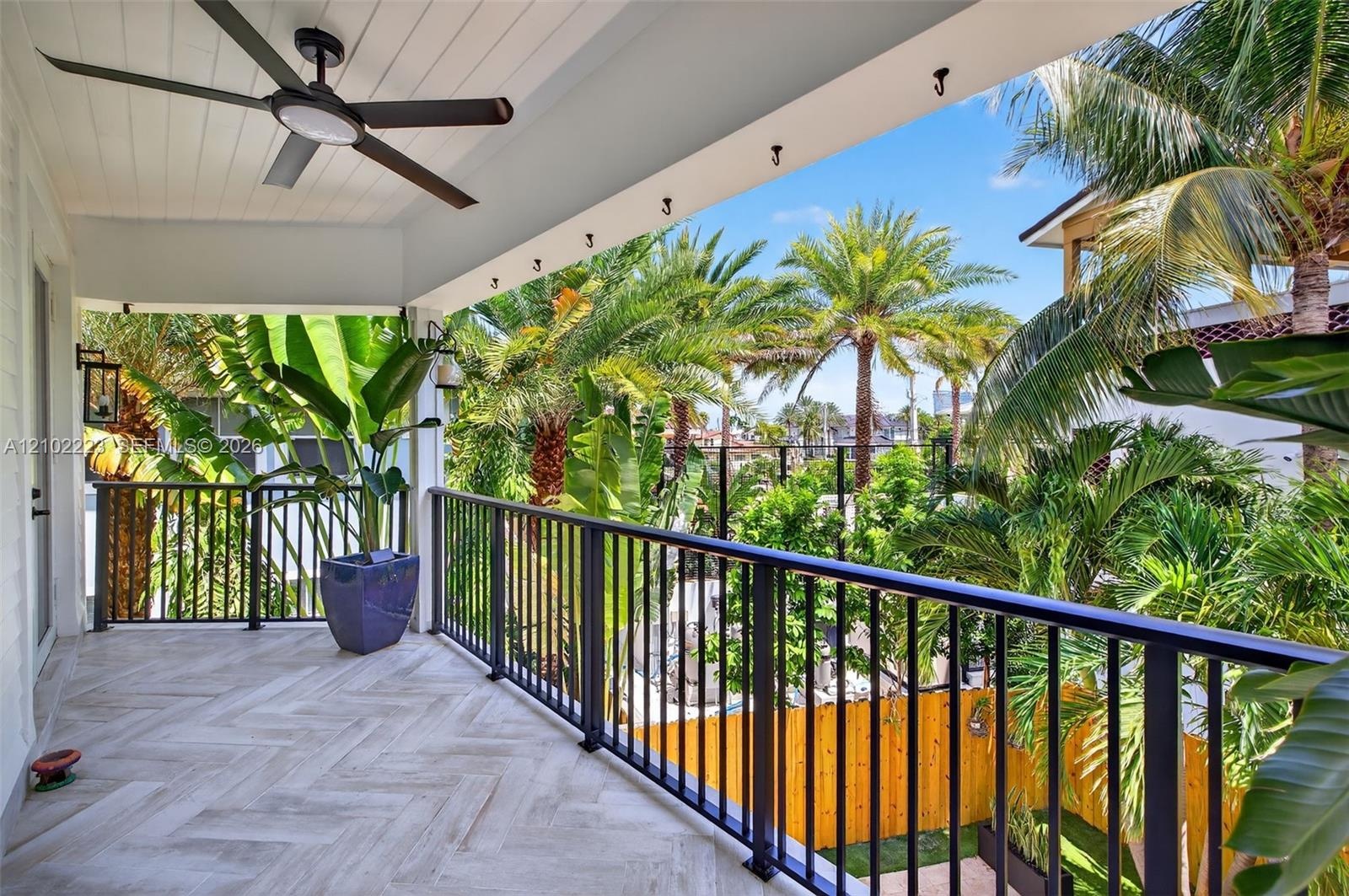 An expansive covered balcony of the primary suite offers a beautiful Tropical escape, surrounded by swaying palms and lush greenery with generous spac