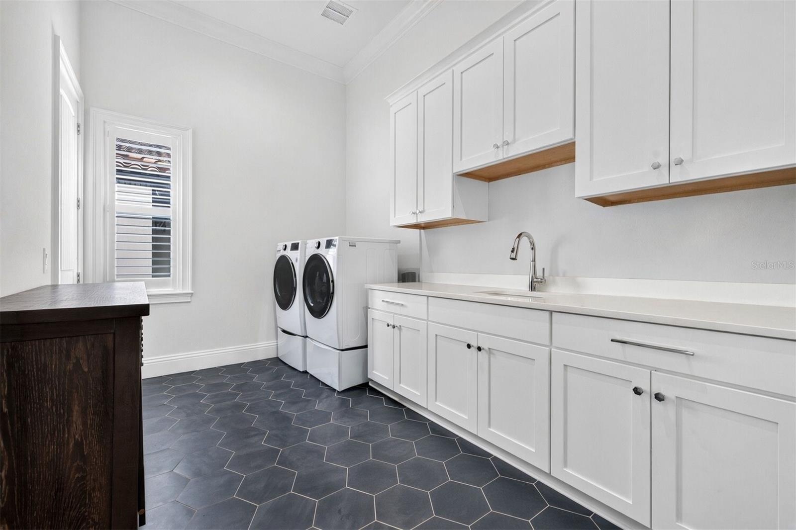 Thoughtfully Designed Laundry Room with Ample Cabinetry and Utility Sink