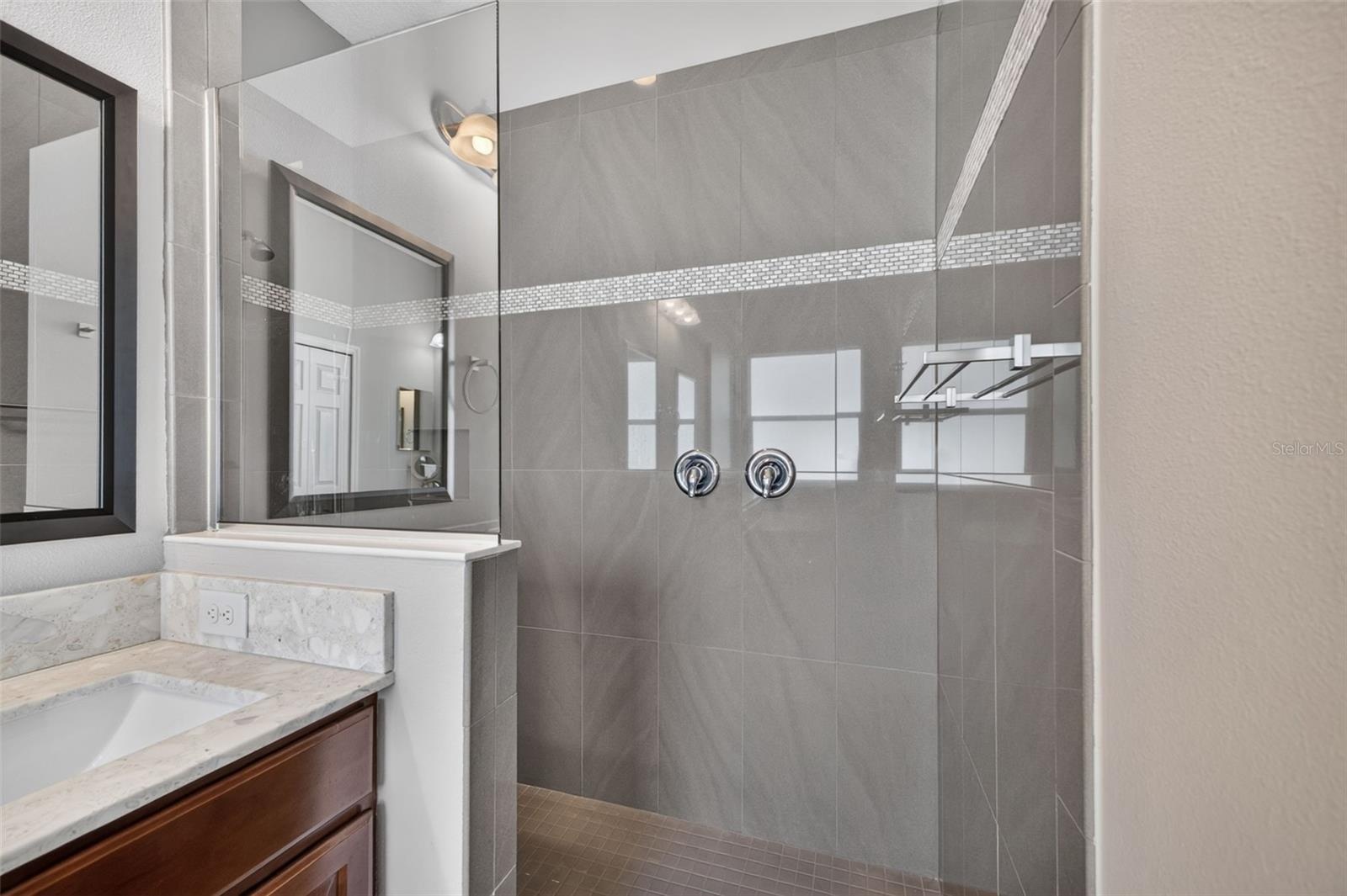 A separate, oversized walk-in shower features elegant tilework, offering a luxurious spa-like experience.