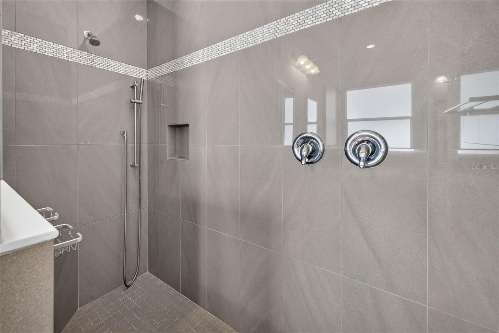 Floor-to-ceiling custom tilework and an accent detail wall give the walk-in shower a striking, spa-like feel.