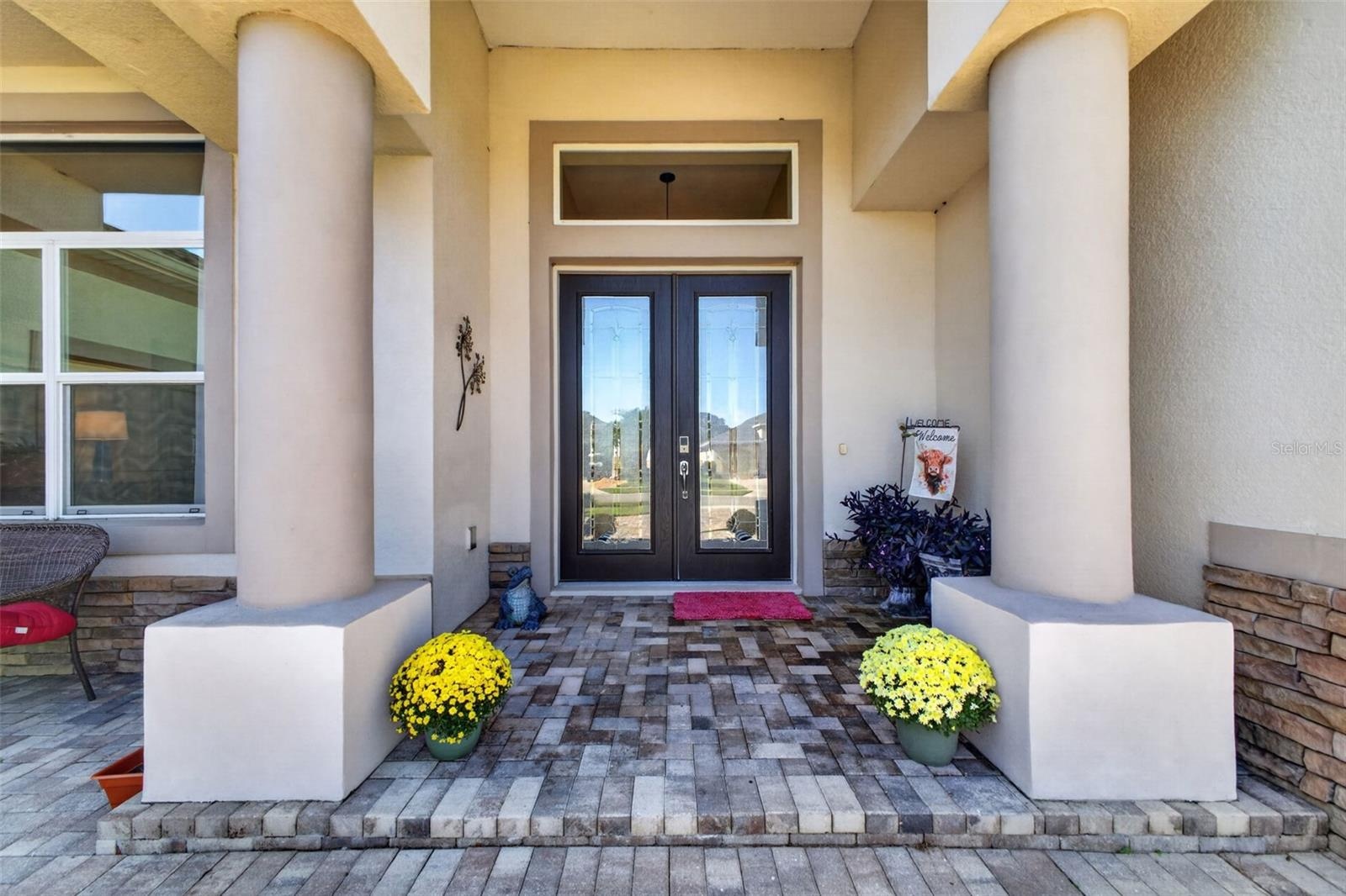 An inviting front porch sets a sophisticated tone upon arrival, complete with beveled glass double doors that seamlessly blend privacy with natural li