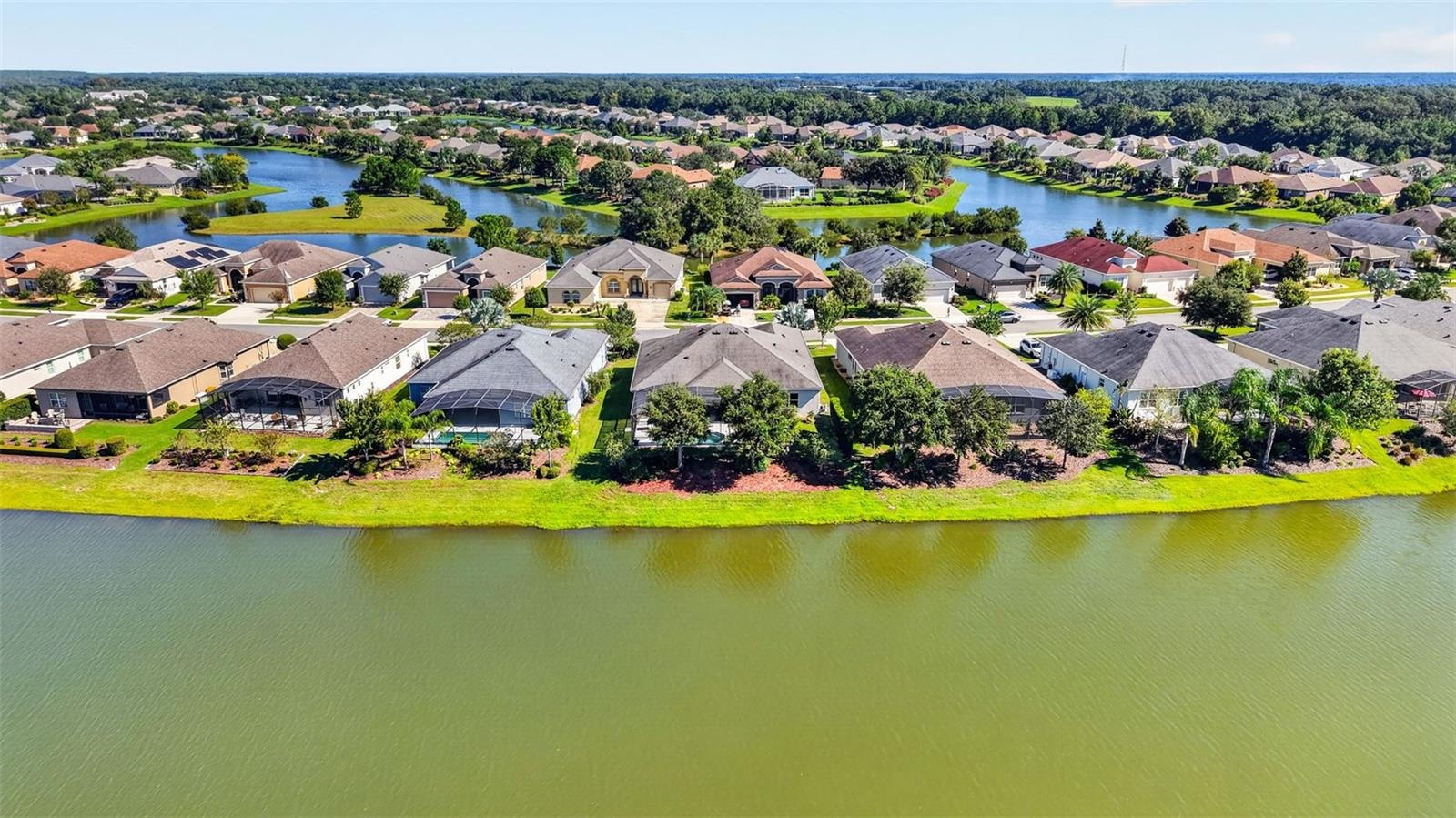 An aerial drone perspective captures the rear elevation of the home, perfectly positioned along the lake.