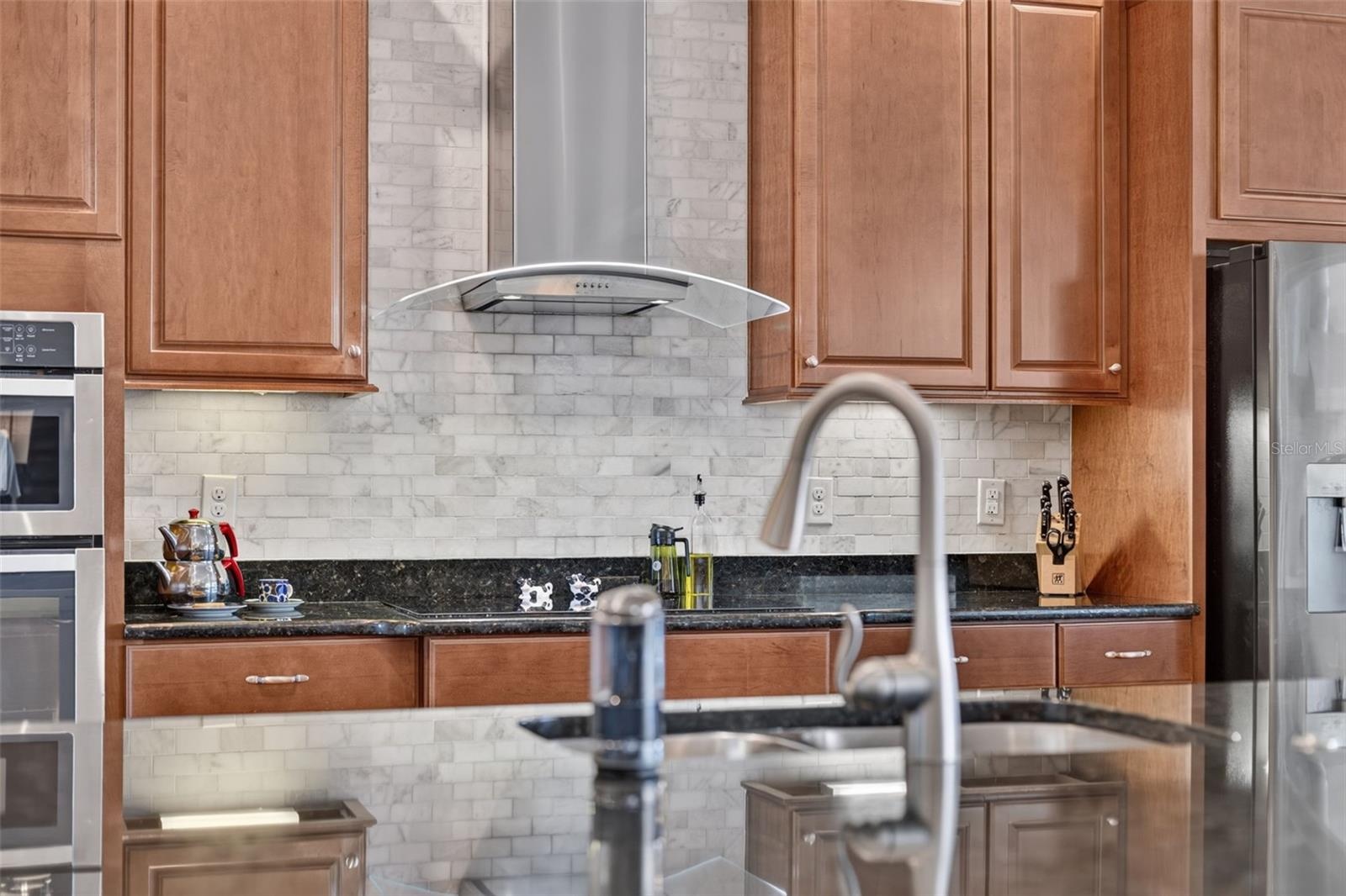 Rich wooden cabinetry, sleek granite countertops, and custom tilework make this gourmet kitchen an absolute chef’s dream.