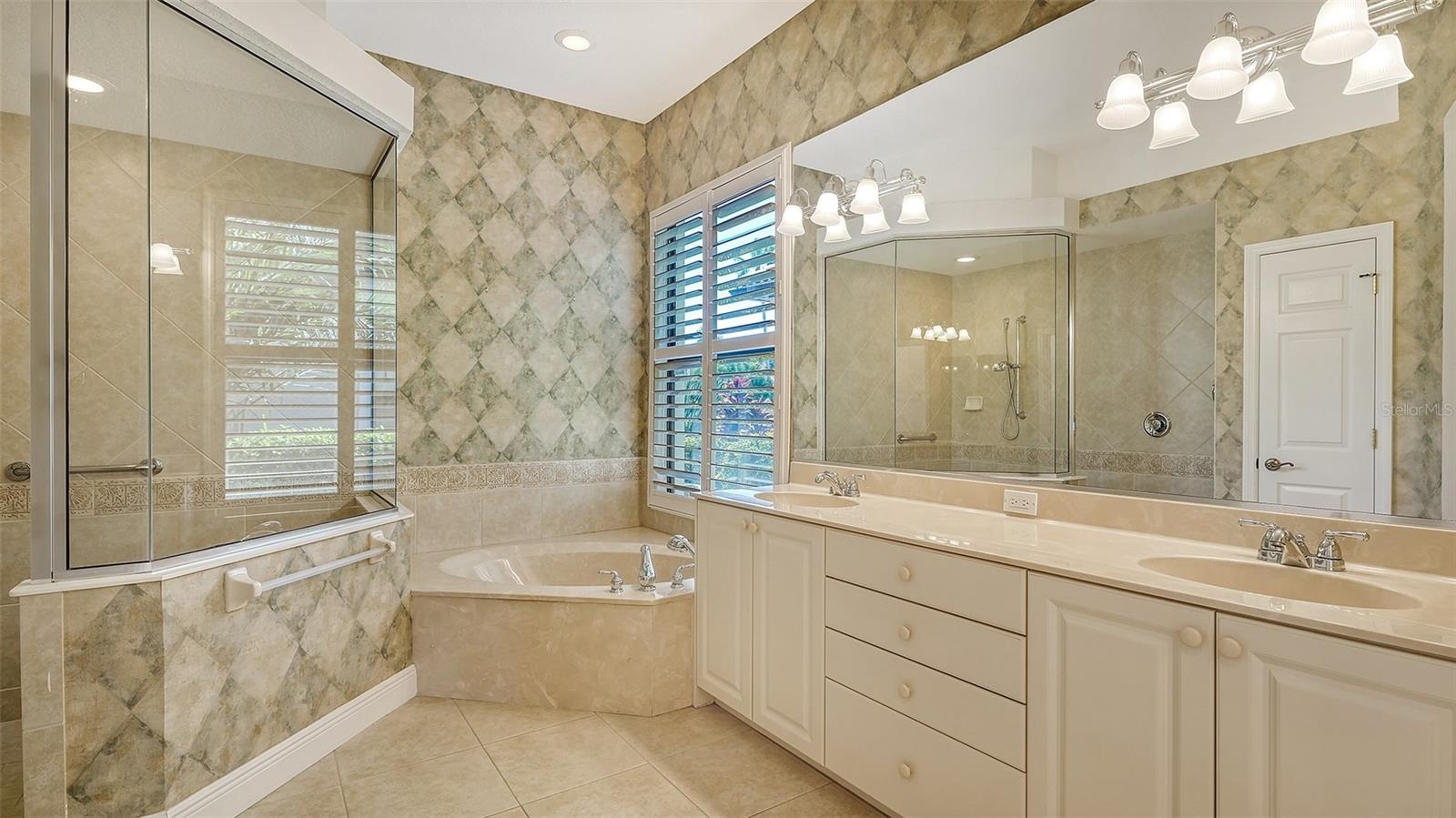 master bathroom with double vanities, soaking tub and walk in shower