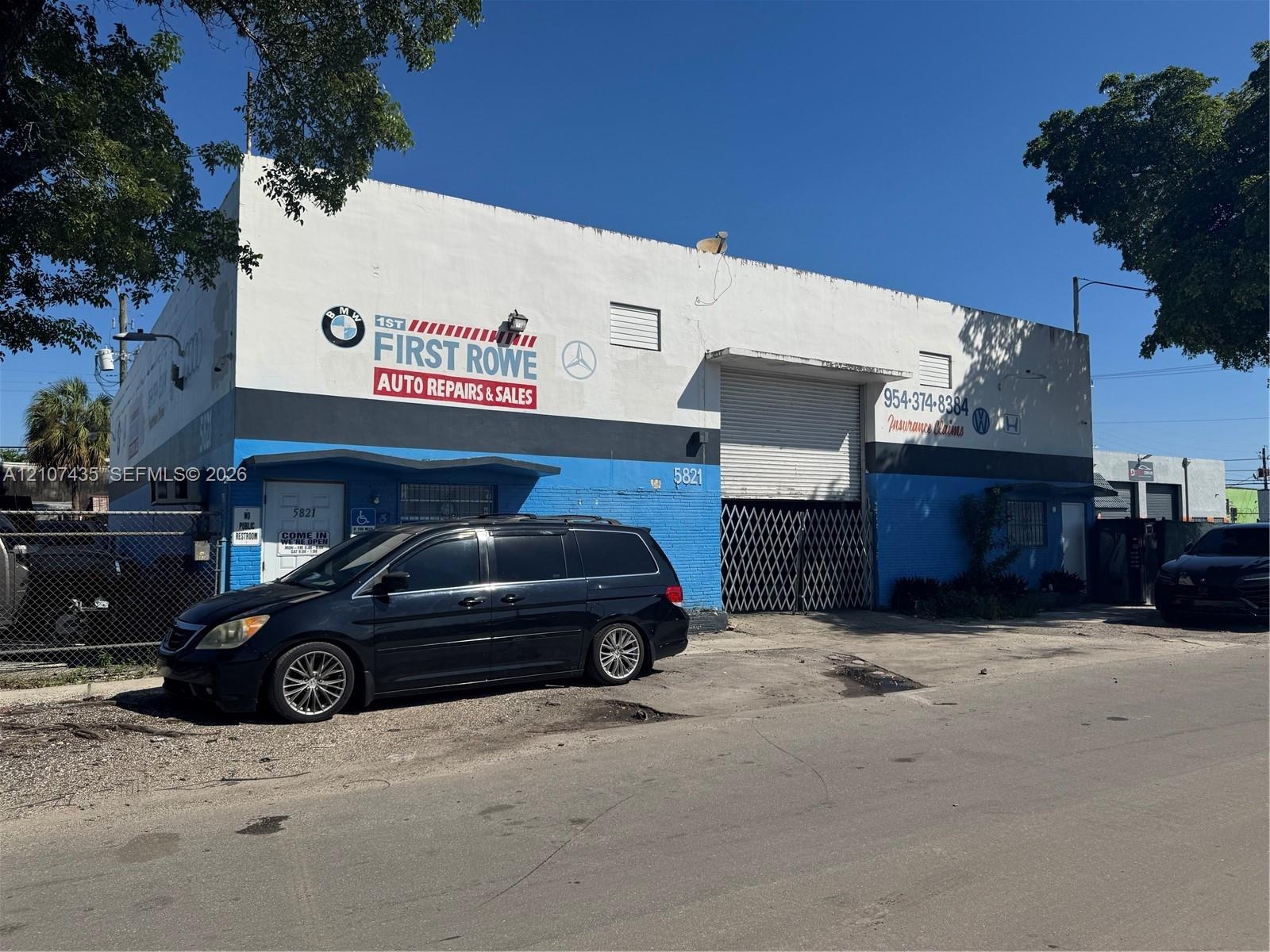 Industrial warehouse building featuring a masonry exterior, high-clearance roll-up door, metal security gate, and paved exterior space