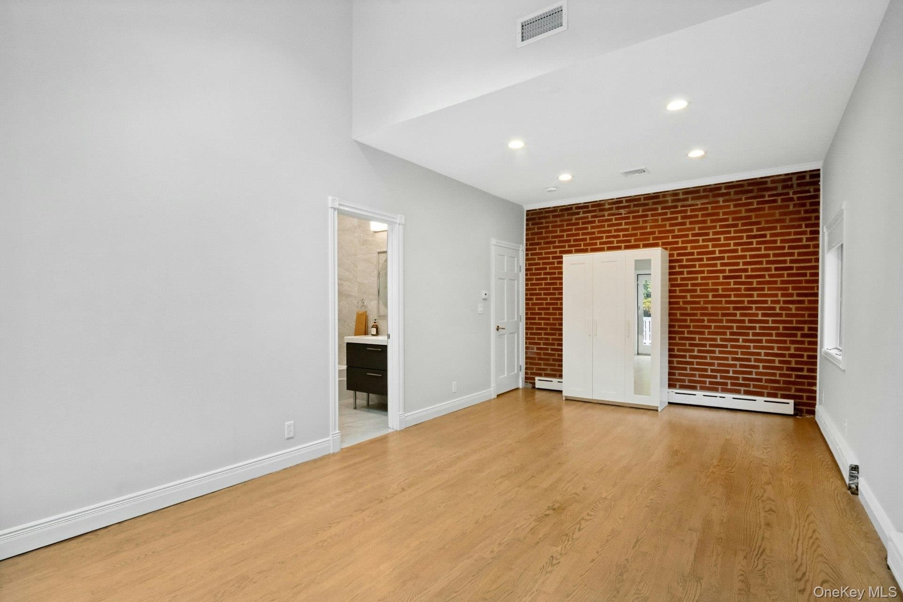 Primary bedroom with brick accent wall.