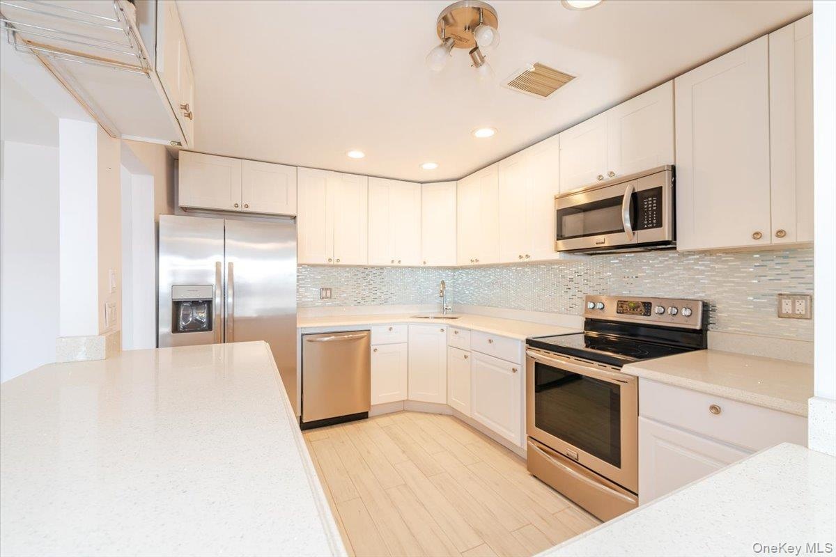Kitchen featuring a sink, visible vents, white cabinets, and stainless steel appliances