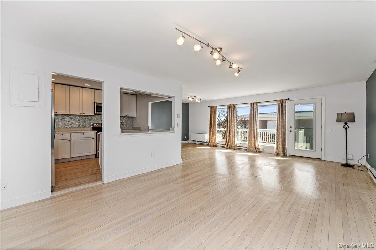 Unfurnished living room featuring light wood finished floors and baseboards
