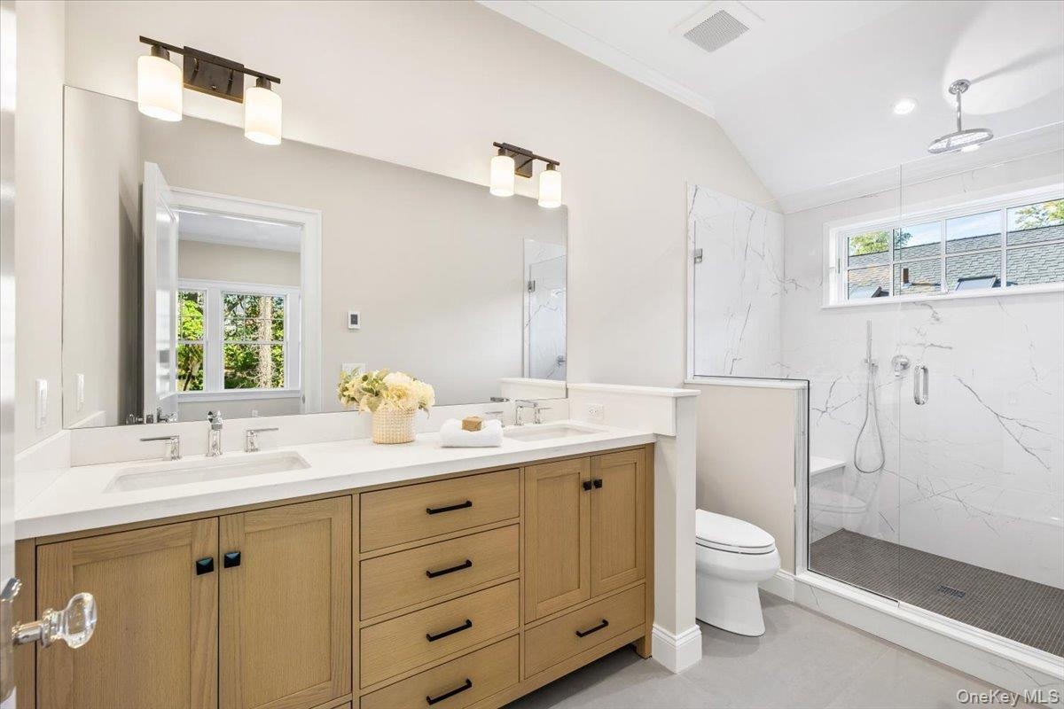 Primary bathroom features large dual vanity, oversized shower, and vaulted ceilings.