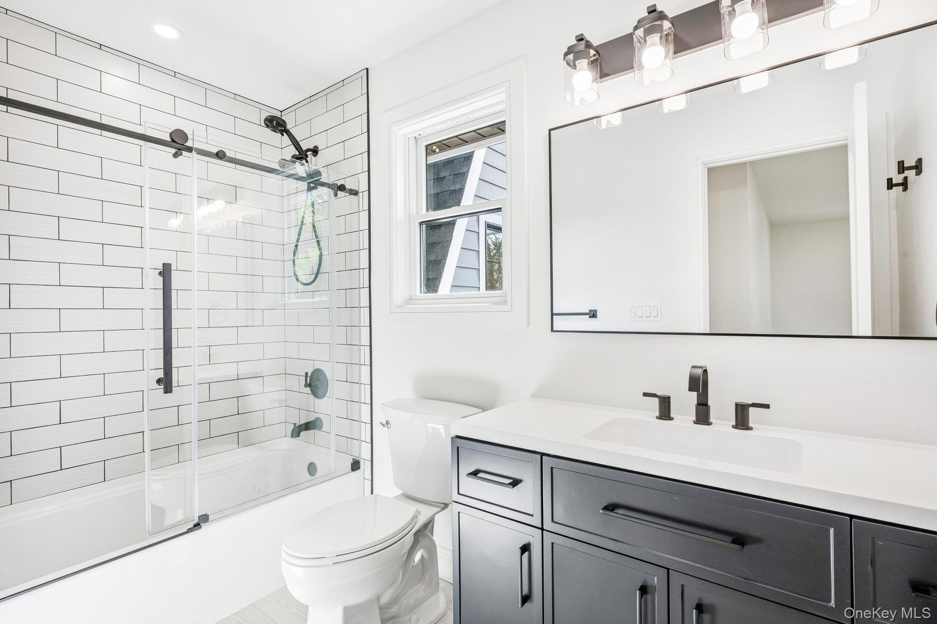 En suite bath #2 of 3 in the home - with a tiled tub and navy vanity. After sandcastles at Corey Beach and a Flo's dog at Flo's Luncheonette, both wel
