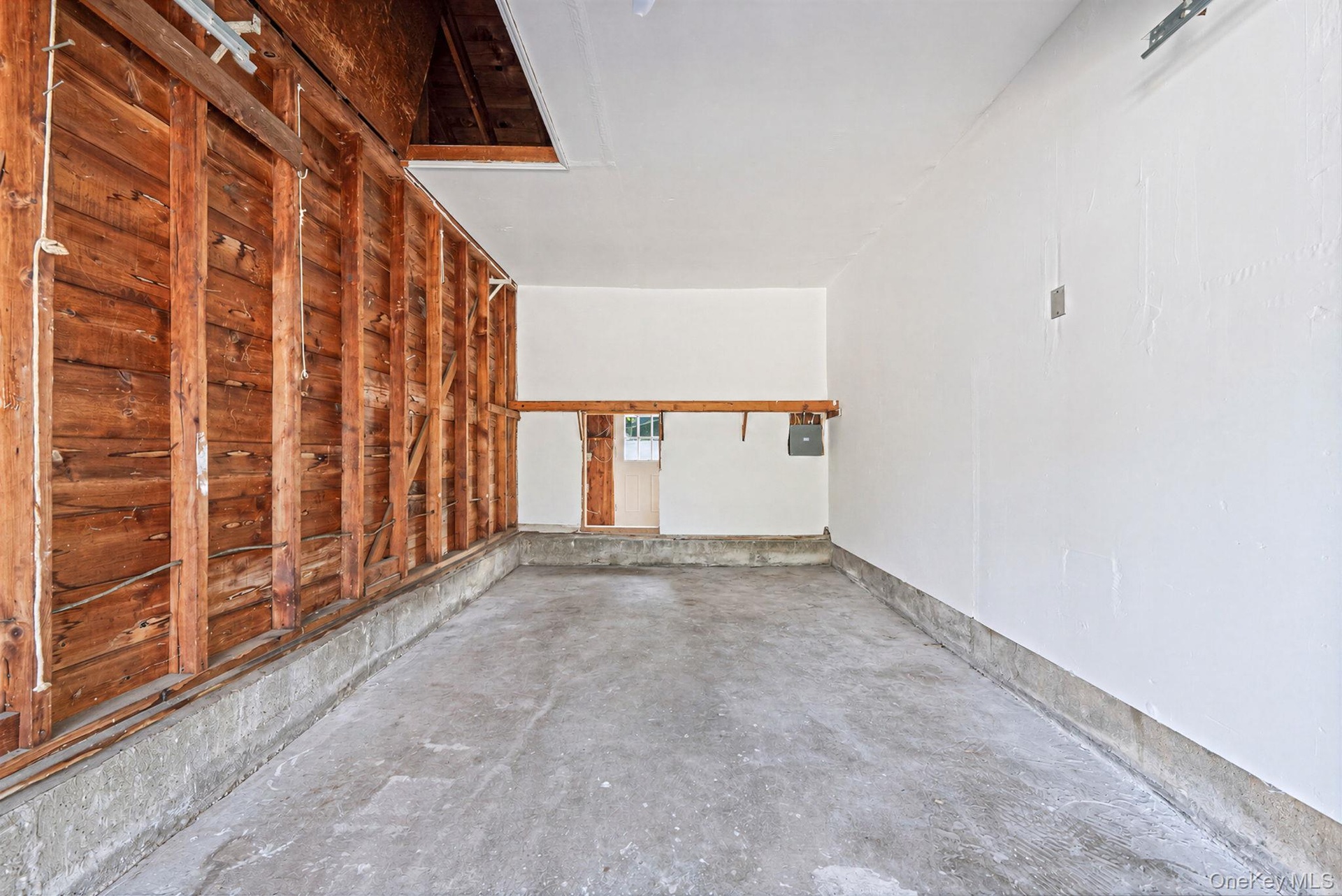 Garage interior featuring white walls, concrete flooring and plenty of space for storage or car