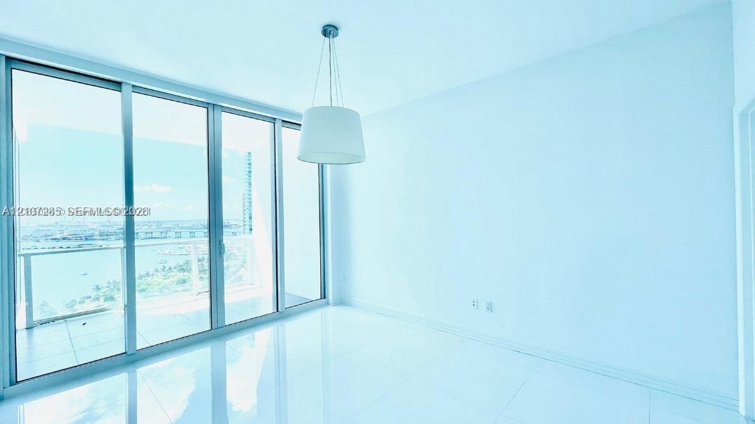 Floor-to-ceiling glass sliding doors, polished tile flooring, pendant lighting, and an expansive balcony