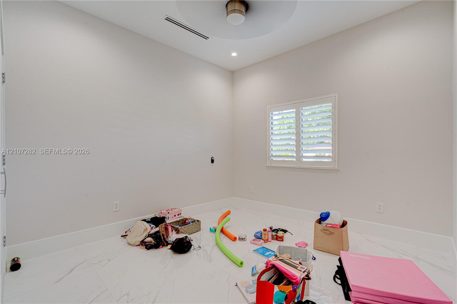 Neutral interior featuring white stone-finish flooring, high ceilings with recessed lighting, and a dual-tone circular light fixture