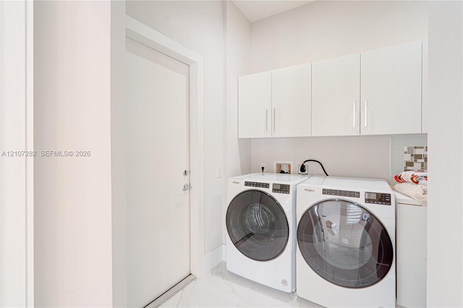 Laundry area featuring white cabinetry, solid-surface flooring, and neutral wall tones