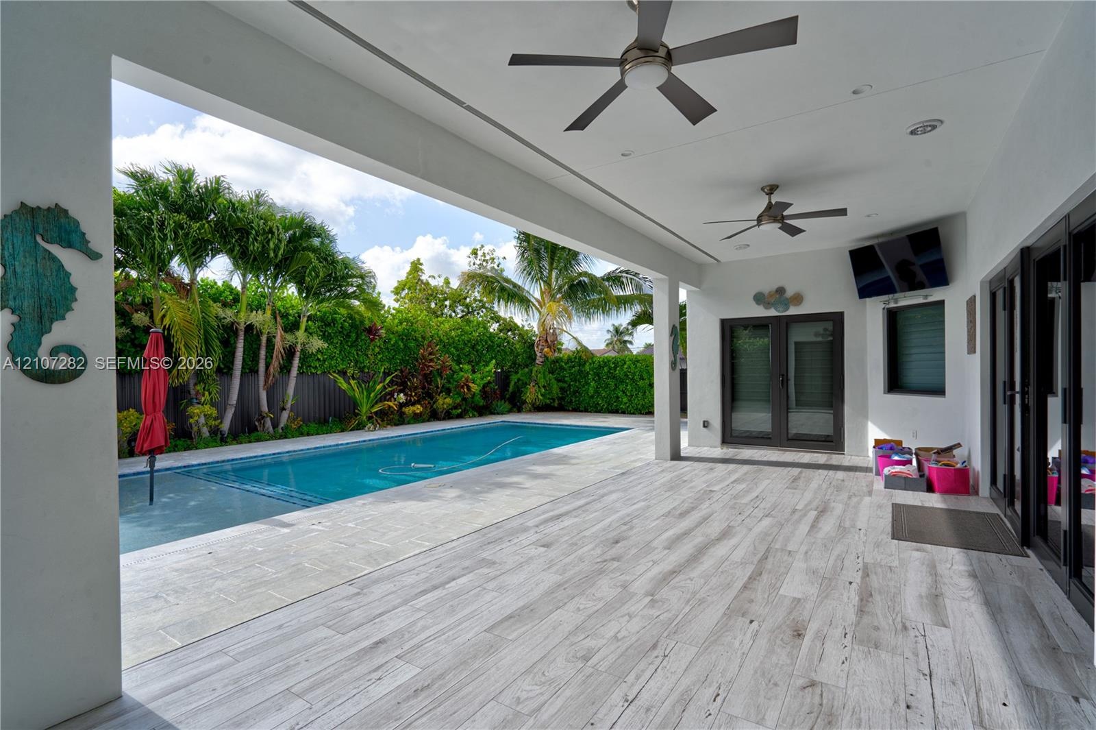 Covered patio featuring wood-finish flooring, dual ceiling fans, recessed lighting, and a private swimming pool