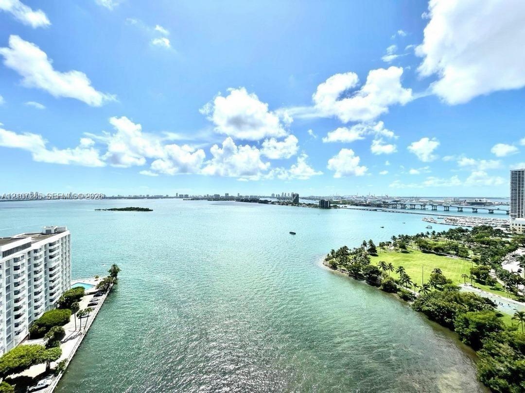 Expansive water expanse featuring a shoreline park, tropical vegetation, and bridge infrastructure
