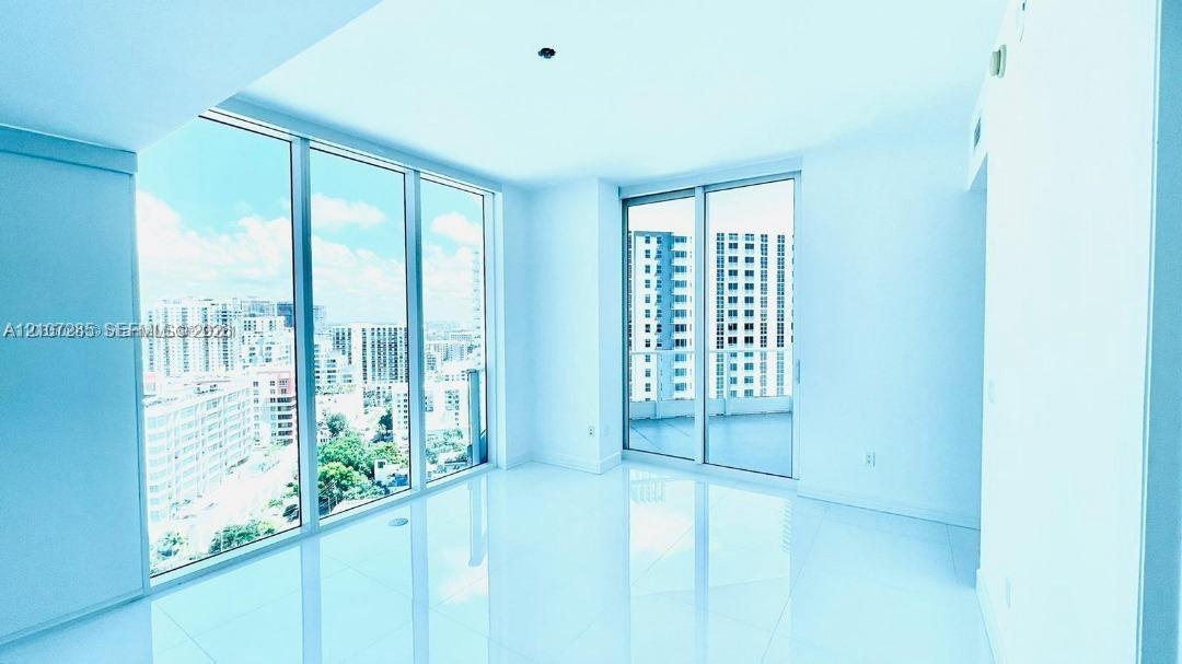 Floor-to-ceiling windows, white tile flooring, and sliding glass doors with direct exterior access