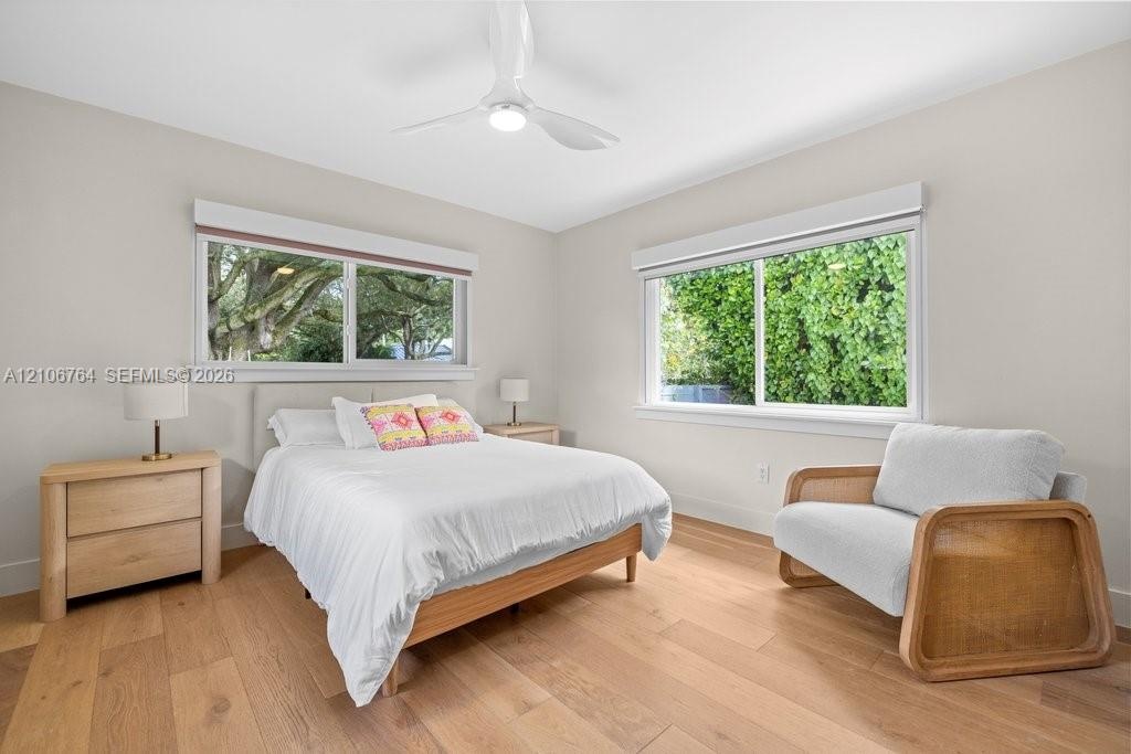 Bedroom featuring wood-finish flooring, two large sliding windows, and a ceiling-mounted light fixture