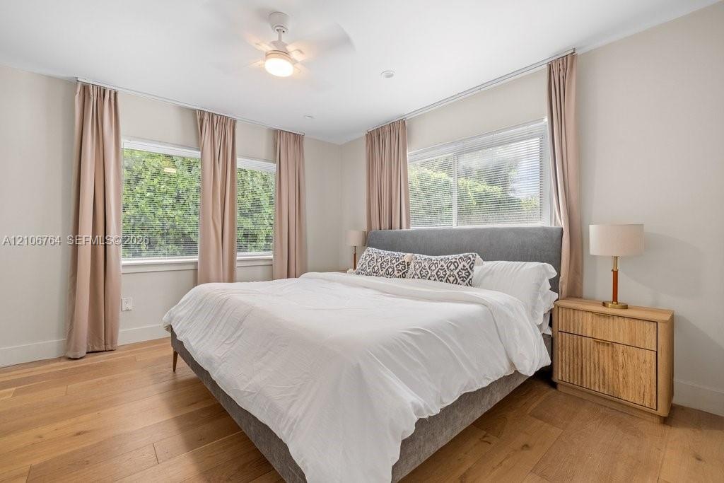 Wood-finish flooring, neutral wall tones, multi-pane sliding windows, and a ceiling fan with integrated light fixture