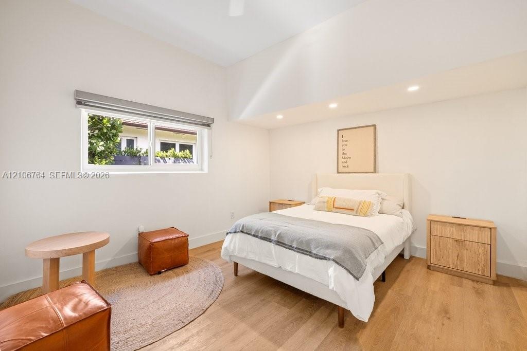 High-ceiling room featuring recessed lighting, wood-finish flooring, and a window with a roller shade