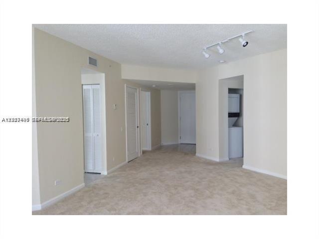 Interior space featuring neutral wall tones, wall-to-wall carpeting, overhead track lighting, louvered closet doors, and a built-in laundry area