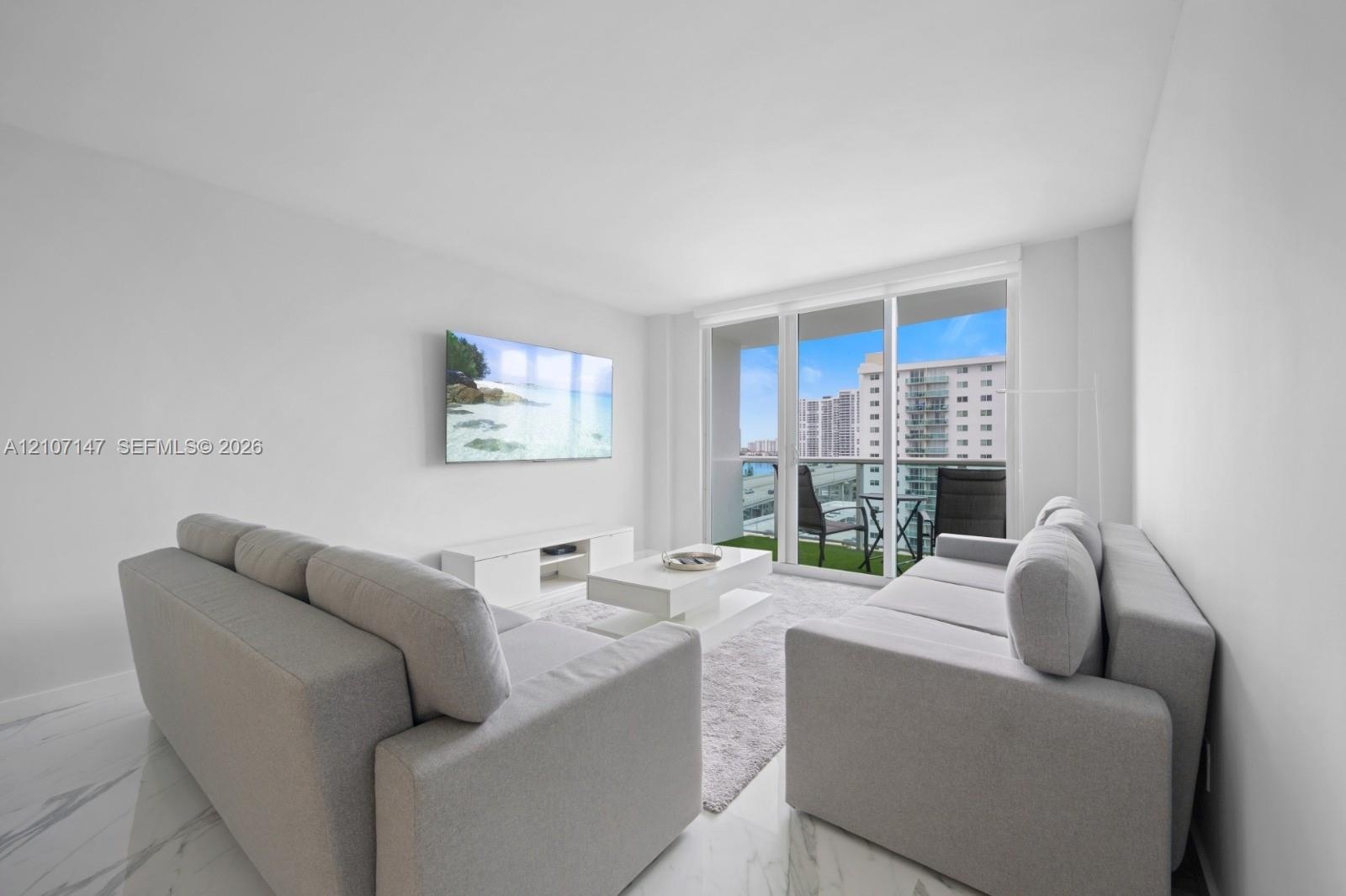Living space featuring stone-finish flooring and floor-to-ceiling glass sliding doors providing access to a private balcony