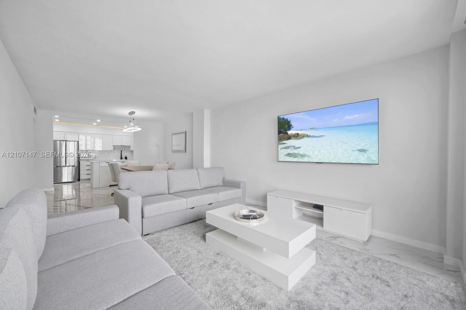 Open-concept area featuring tile flooring, white cabinetry, stainless steel kitchen appliances, and recessed ceiling lighting