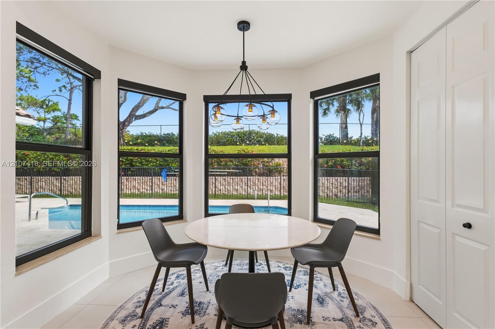 Bay window featuring floor-to-ceiling windows with black frames, tile flooring, and a multi-arm modern chandelier